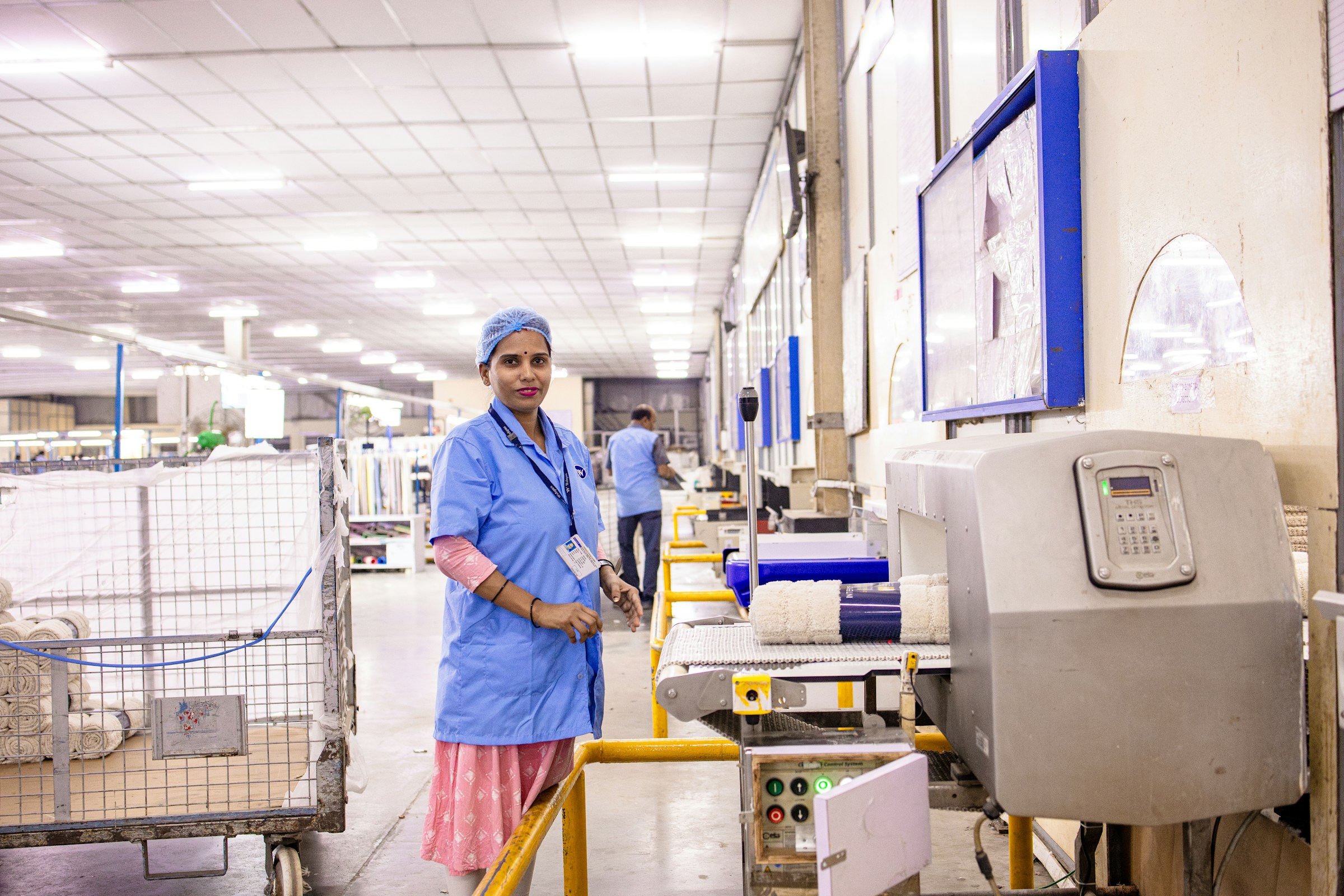 Line operator in a hairnet at a control unit on a clean production floor